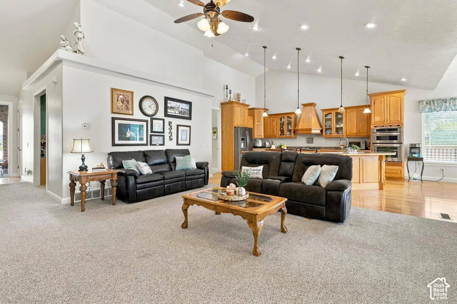 Vaulted ceilings, recessed lighting, natural wood cabinetry, integrated double wall ovens, and pendant lighting over a kitchen island