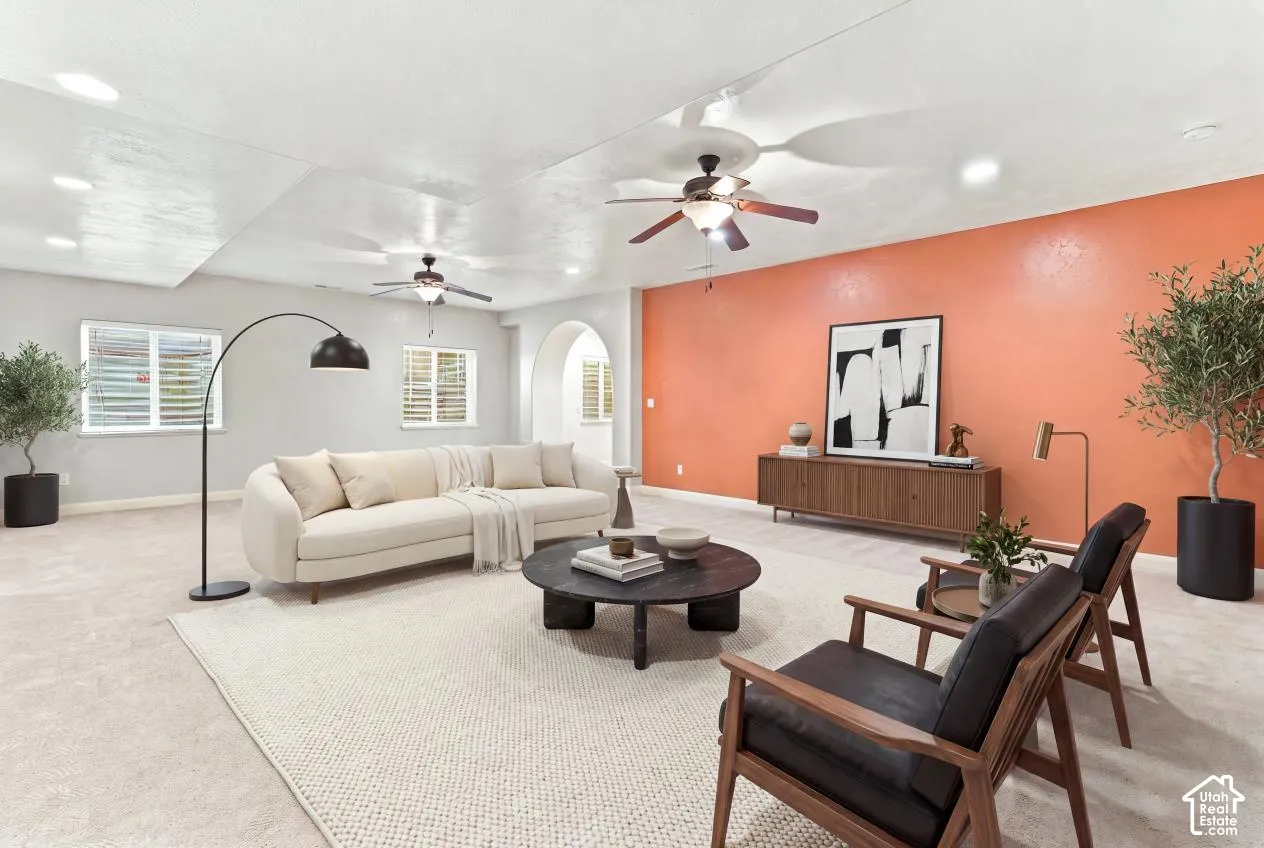 Spacious room featuring a prominent accent wall, dual ceiling fans, recessed lighting, and an arched architectural opening