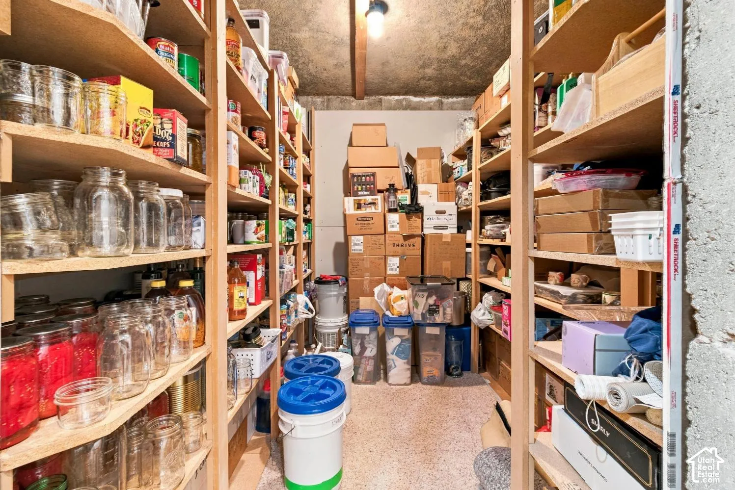 Dedicated storage room featuring floor-to-ceiling built-in wood shelving and concrete wall construction