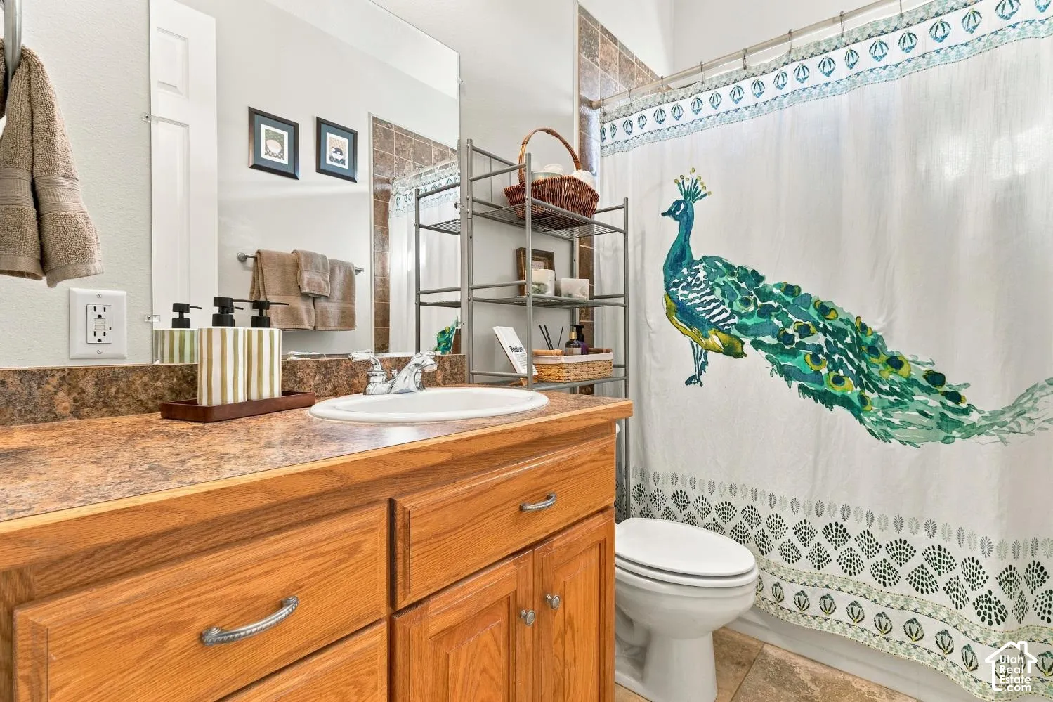 Bathroom vanity with wood-finish cabinetry, solid-surface countertop, integrated basin, and large-format wall mirror, complemented by stone-finish tile surround in the tub area
