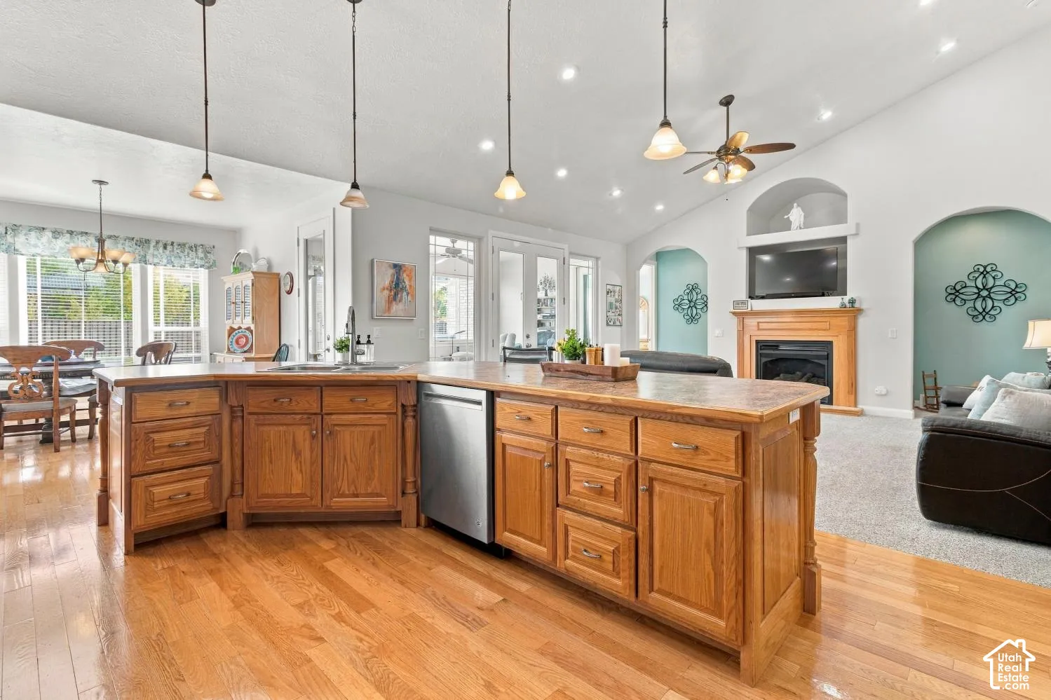 Kitchen featuring a large central island with wood cabinetry, stainless steel dishwasher, recessed lighting, and vaulted ceilings