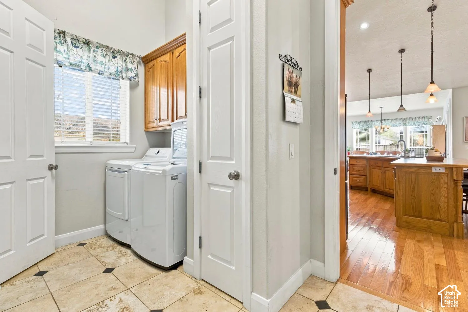 Laundry room featuring natural stone-finish tile flooring, built-in upper cabinetry, and a window for natural light