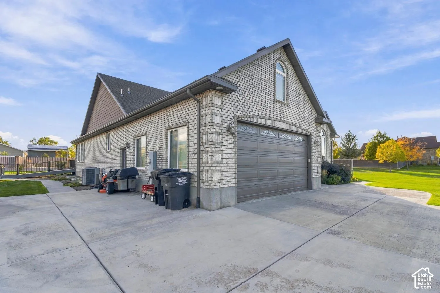 Brick exterior with a gabled roofline, concrete driveway, and attached multi-car garage featuring a decorative arched window