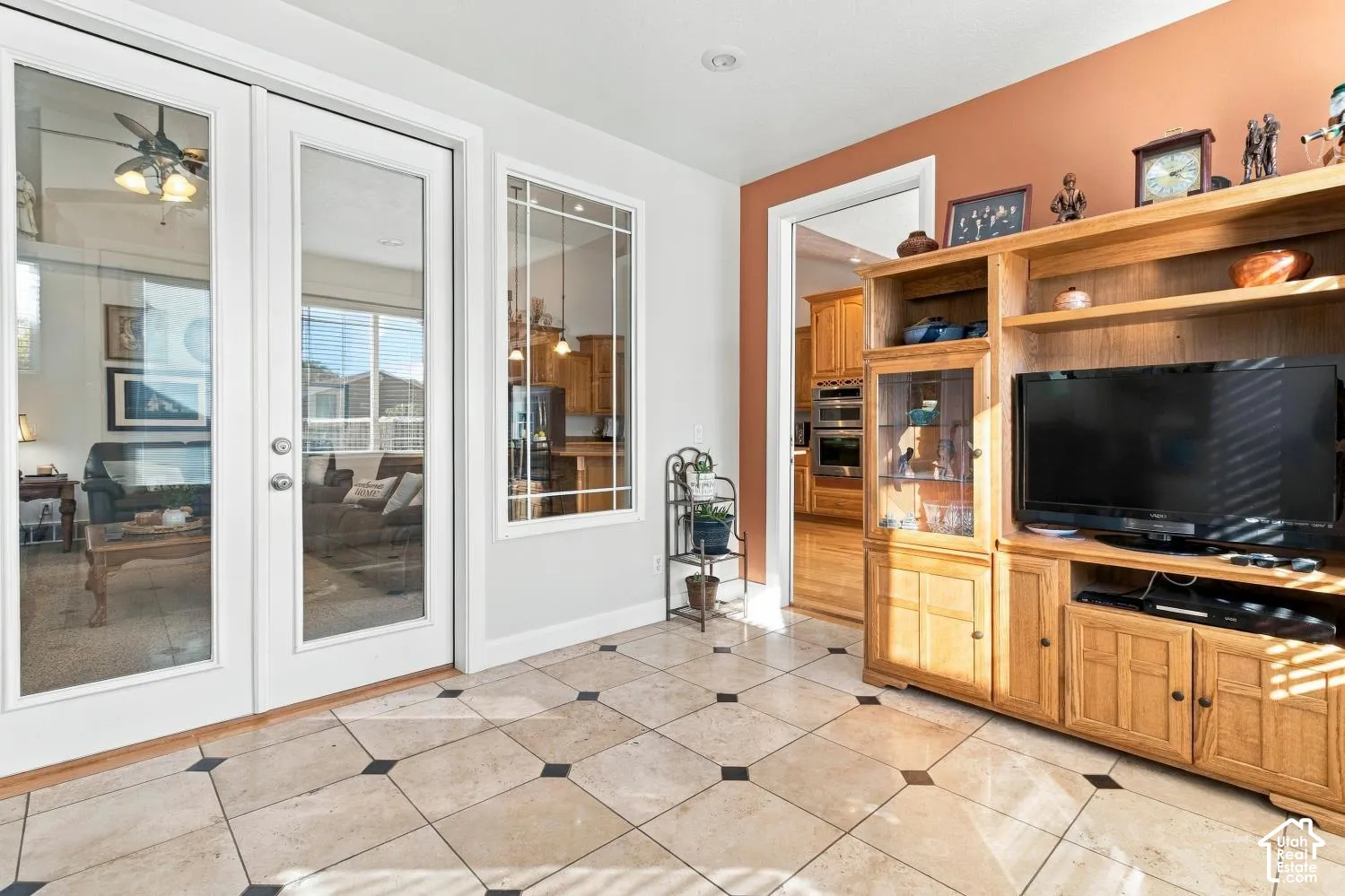 Light-toned tile flooring with contrasting dark inlay accents, glass-paned double French doors, a fixed rectangular window with multi-pane grille design, and recessed ceiling lighting