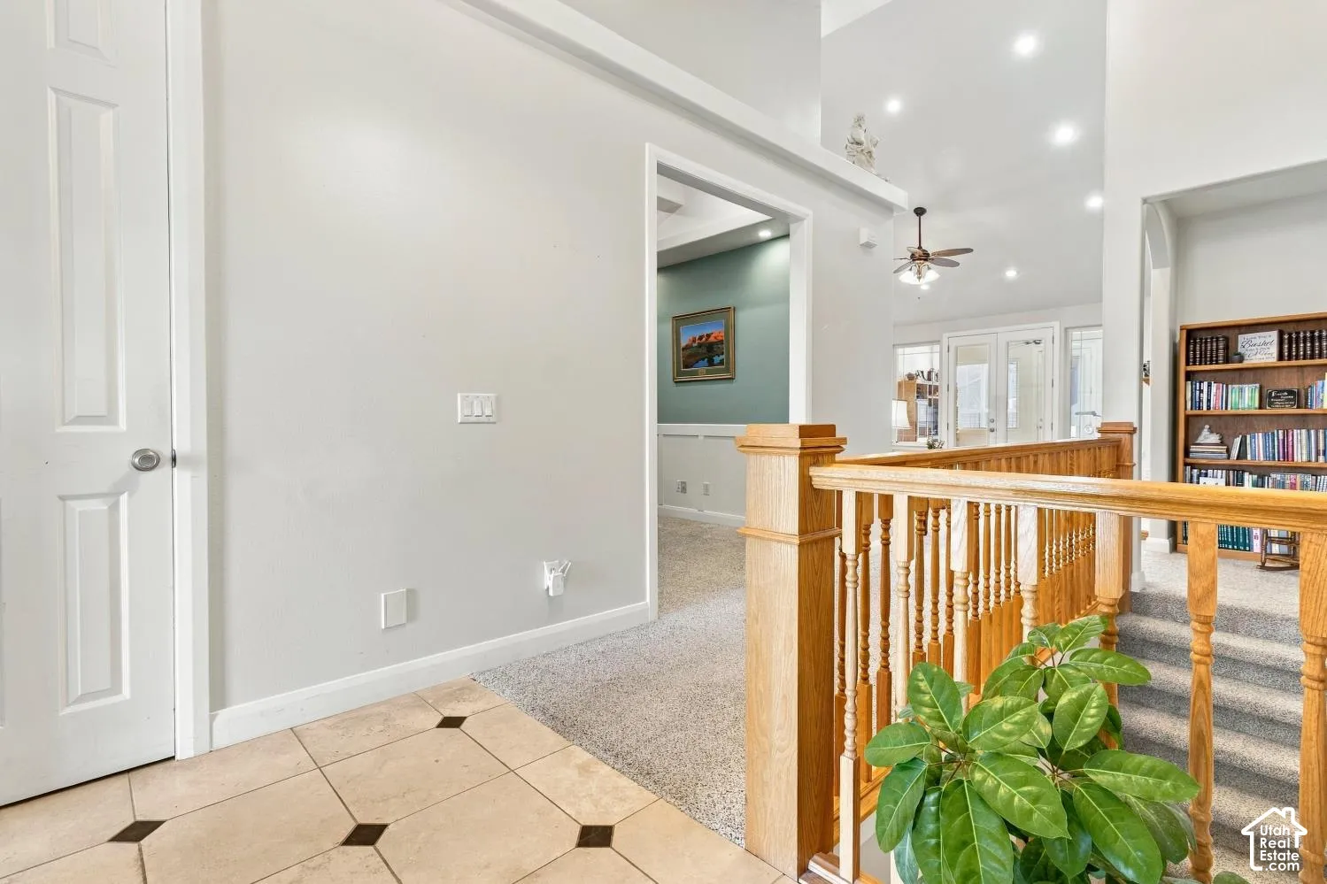 Interior landing featuring tile flooring with decorative stone inlays, vaulted ceilings with recessed lighting, and a solid wood railing with square balusters