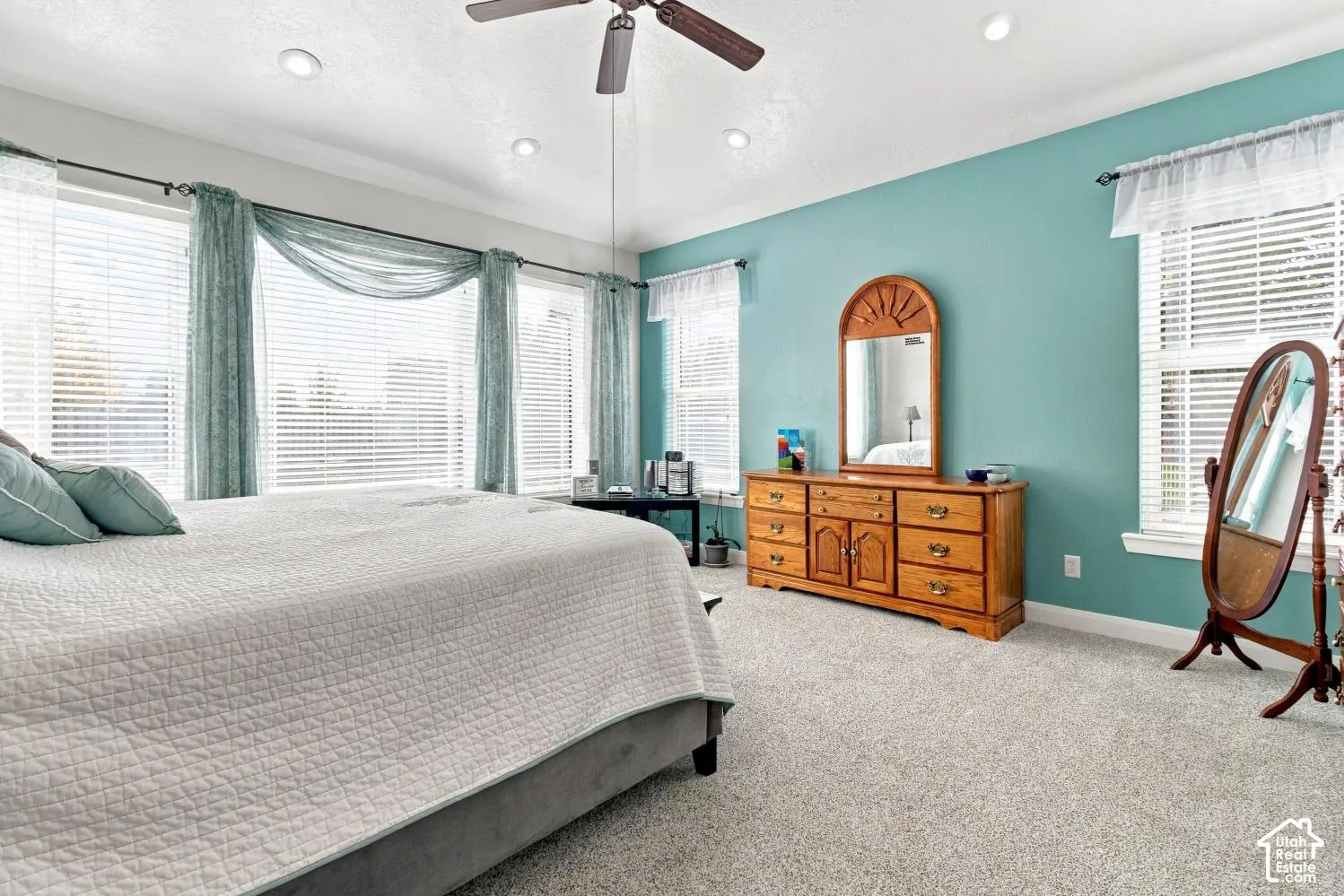 Neutral wall-to-wall carpeting, recessed ceiling lighting, ceiling fan, and multiple windows with horizontal blinds