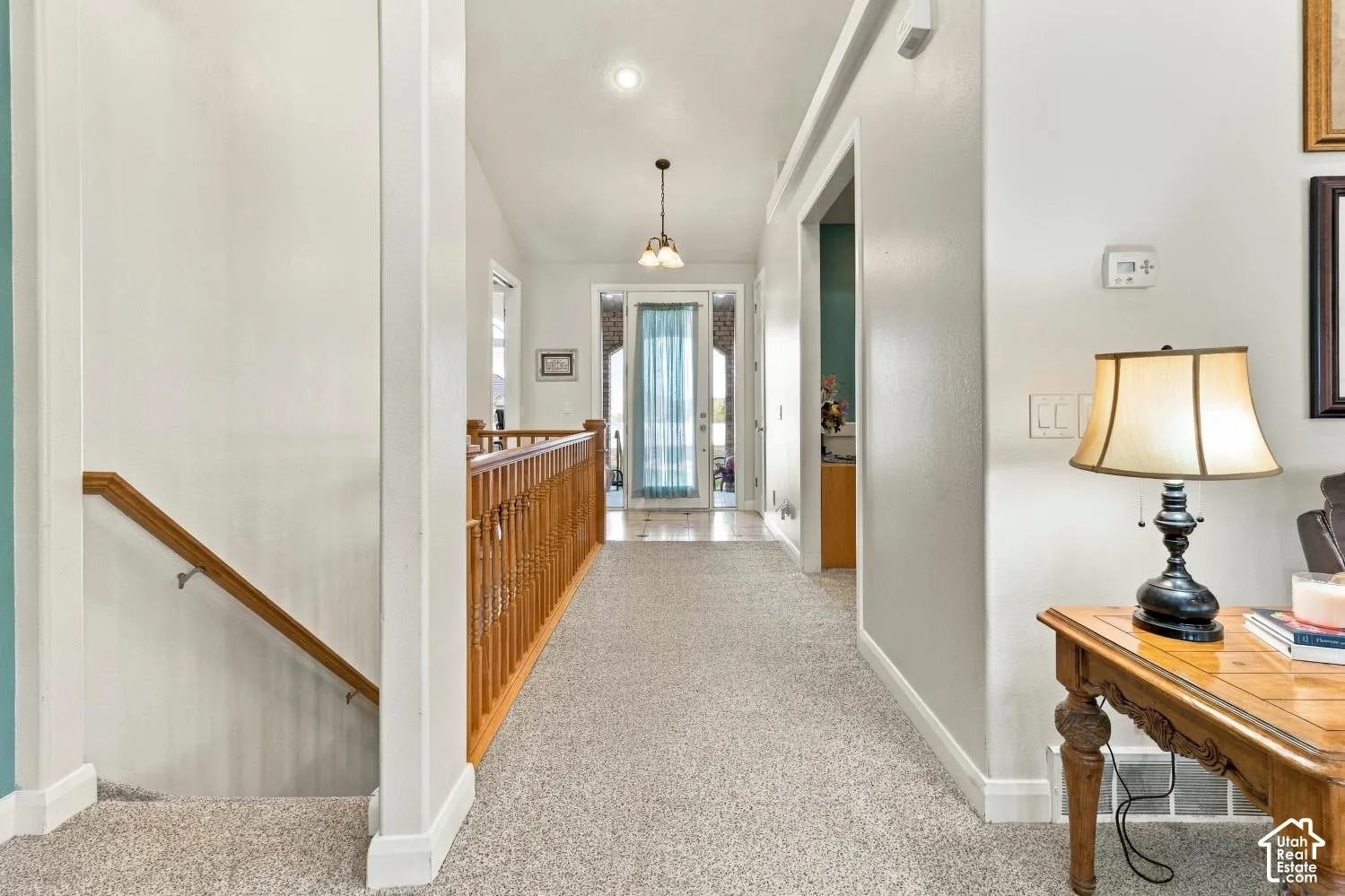 Entryway featuring vaulted ceilings, a glass-panel front door, neutral carpeting, and a wooden stair railing with a mounted handrail