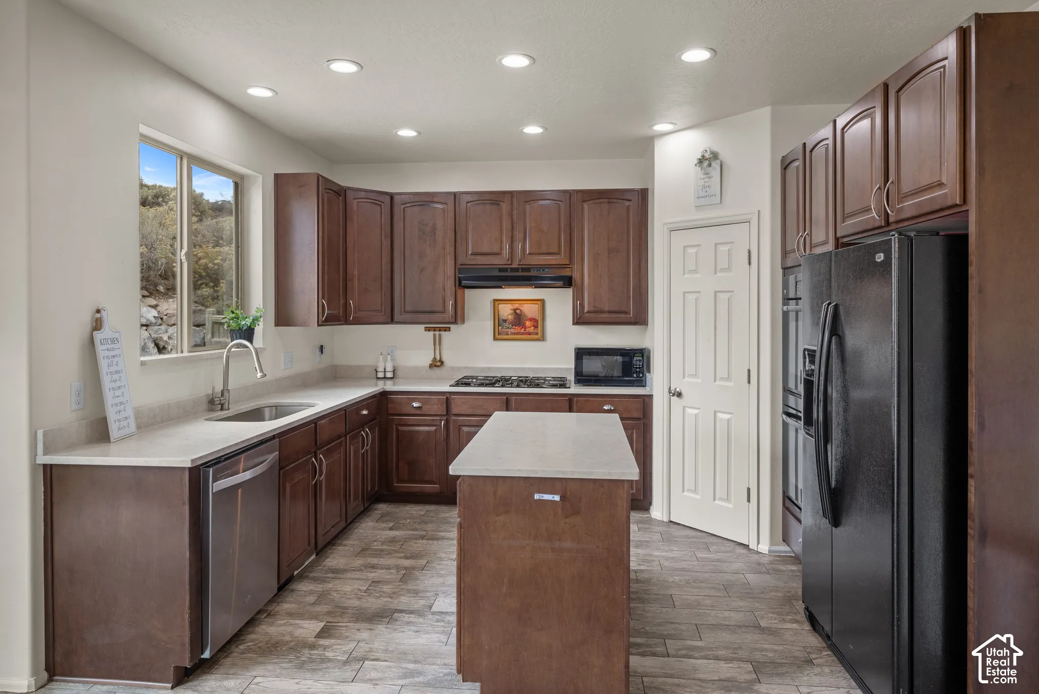 Kitchen featuring dark wood cabinetry, a center island with solid-surface countertops, recessed lighting, and tile flooring
