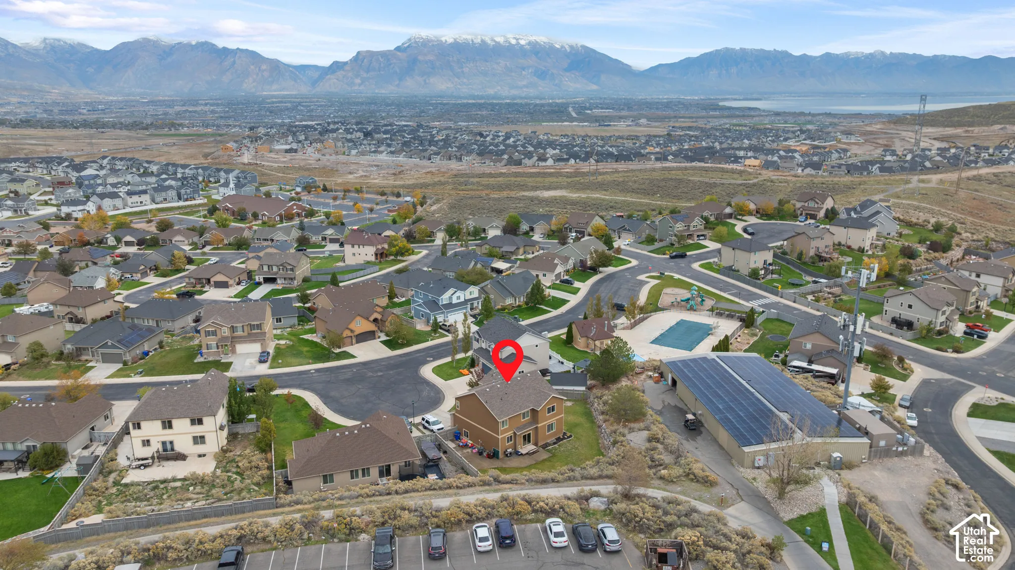 Aerial perspective featuring a two-story residential structure with a shingled roof, set against a mountainous backdrop