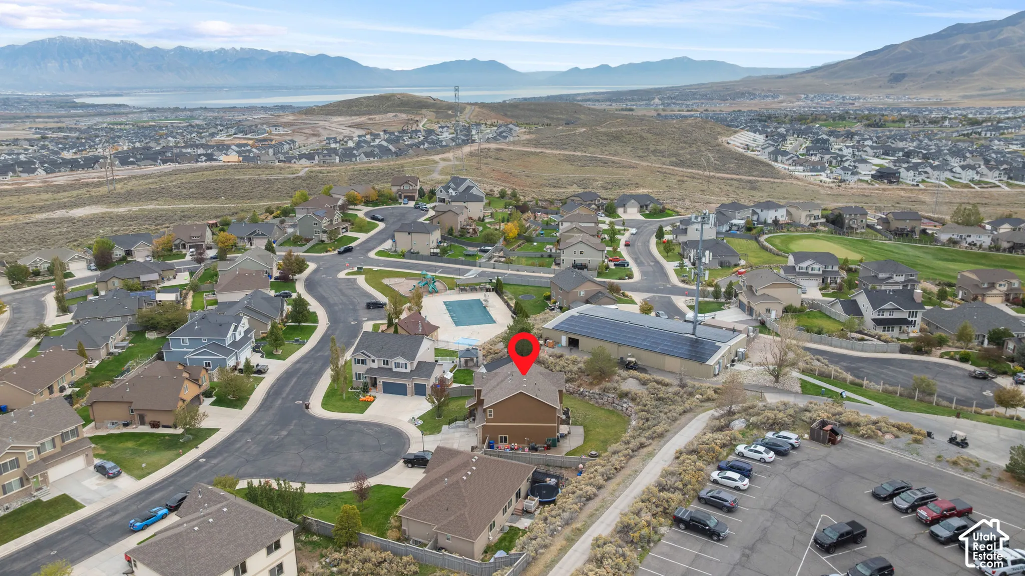 Elevated aerial perspective featuring a multi-story residential structure, hillside topography, and expansive mountain and valley scenery