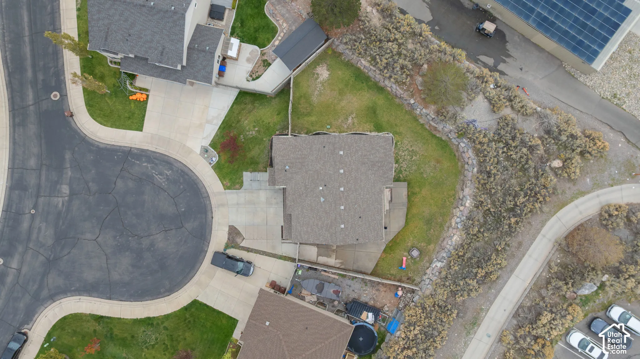 Aerial perspective of a residential property featuring a cul-de-sac location, concrete driveway, multi-pitched shingle roof, and expansive grass lot