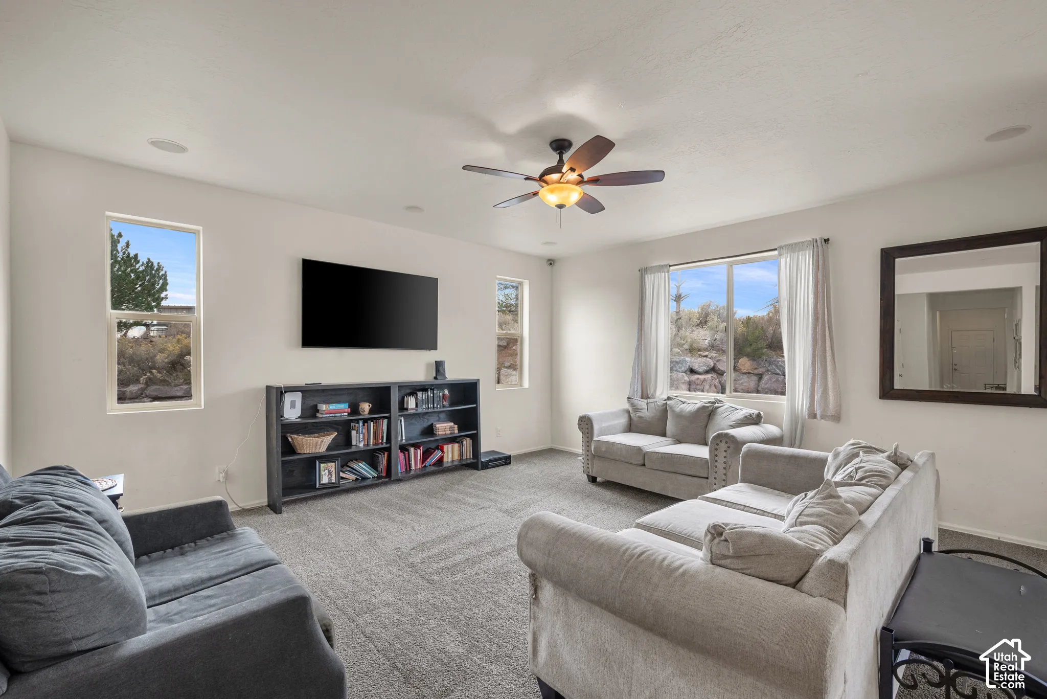 Living area featuring neutral-toned carpeting, recessed lighting, and a multi-blade ceiling fan with integrated light fixture