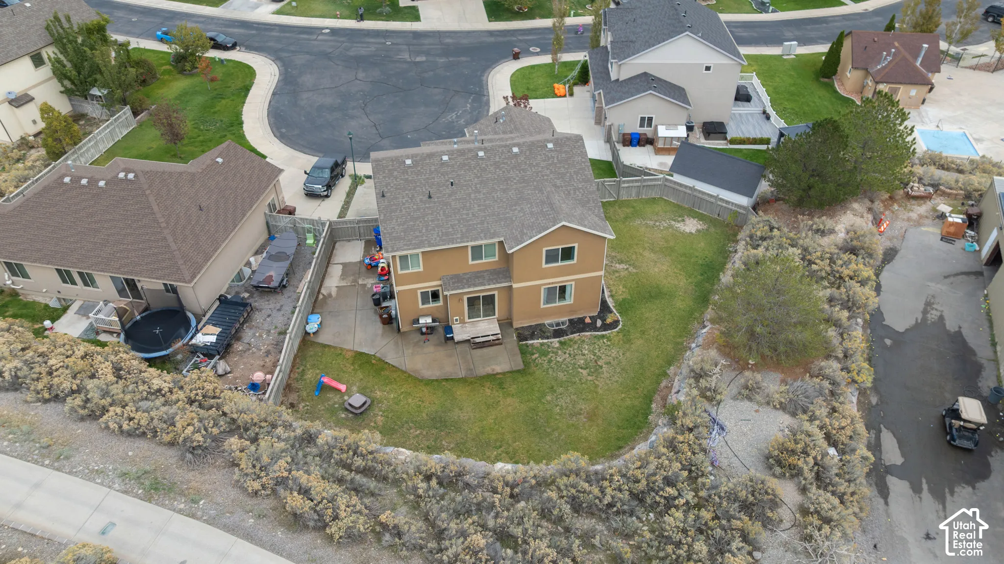 Two-story residence featuring a shingled roof, neutral-toned siding, concrete rear patio, perimeter wood fencing, and a fenced yard