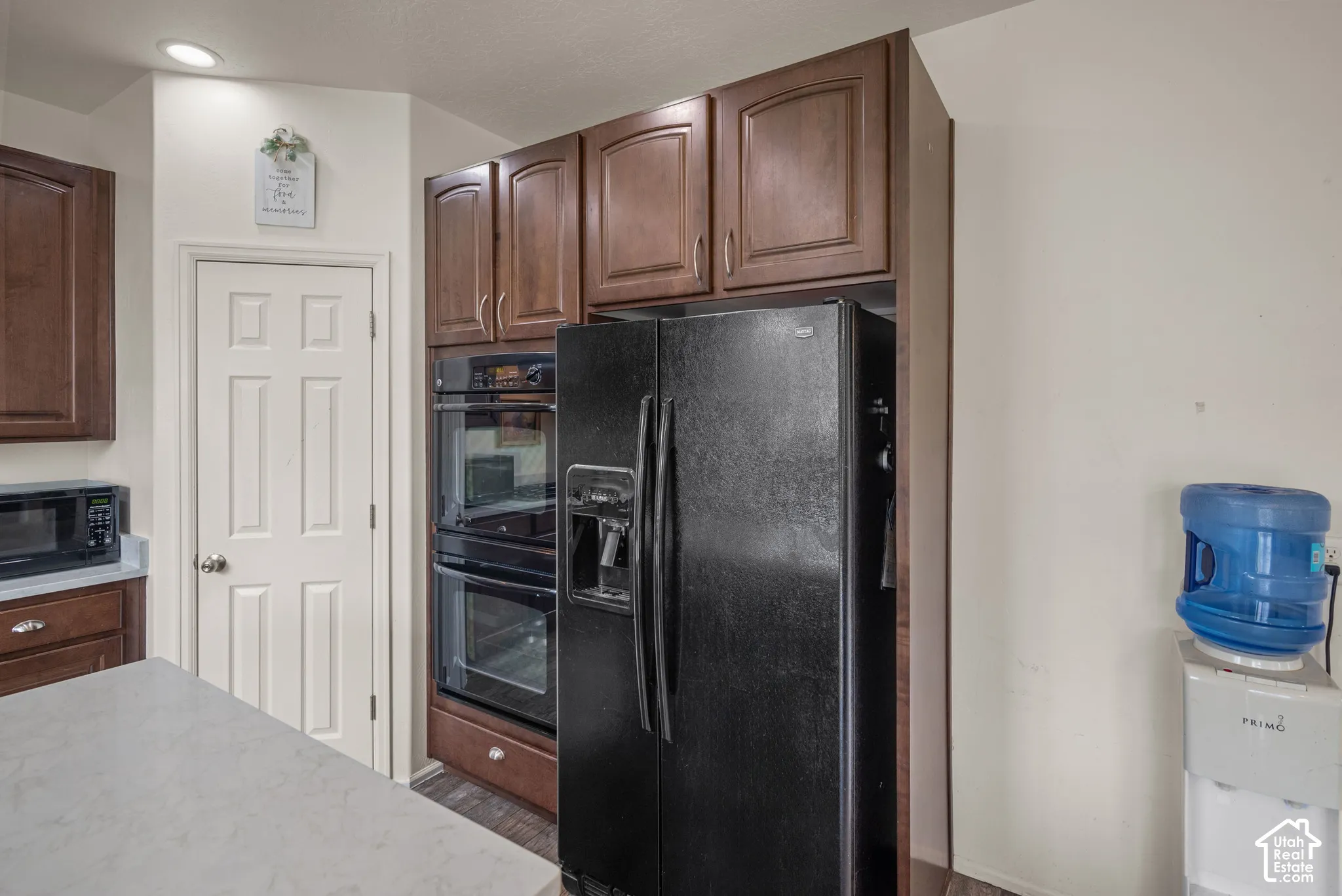 Kitchen featuring raised-panel wood cabinetry, built-in double wall ovens, recessed lighting, and a stone-surface island countertop