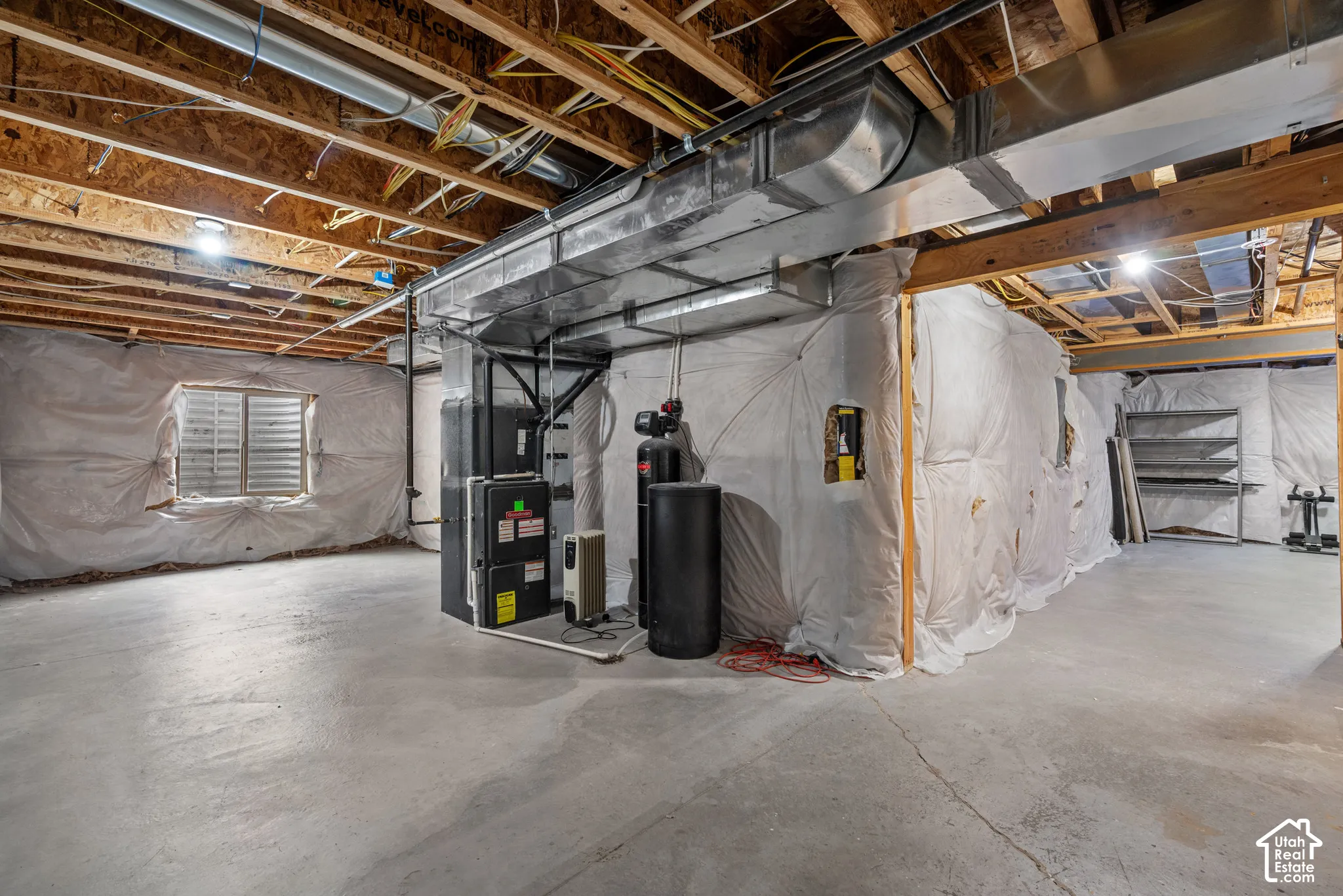 Unfinished lower level featuring concrete flooring, exposed joist ceiling, wall insulation vapor barriers, metal ductwork, and mechanical systems