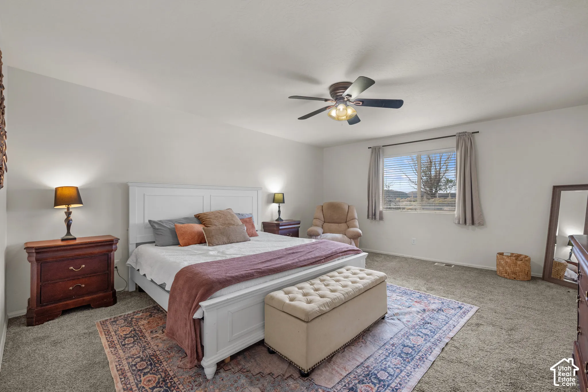Neutral-toned bedroom featuring carpeting, a center-mounted ceiling fan with integrated lighting, and a large window