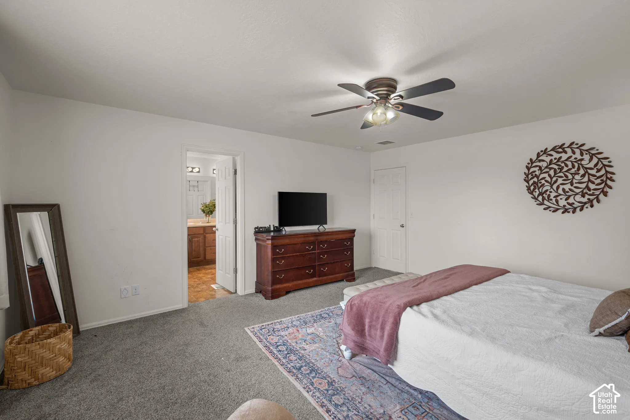 Neutral-toned bedroom featuring plush wall-to-wall carpeting, a multi-blade ceiling fan with integrated lighting, and interior doors