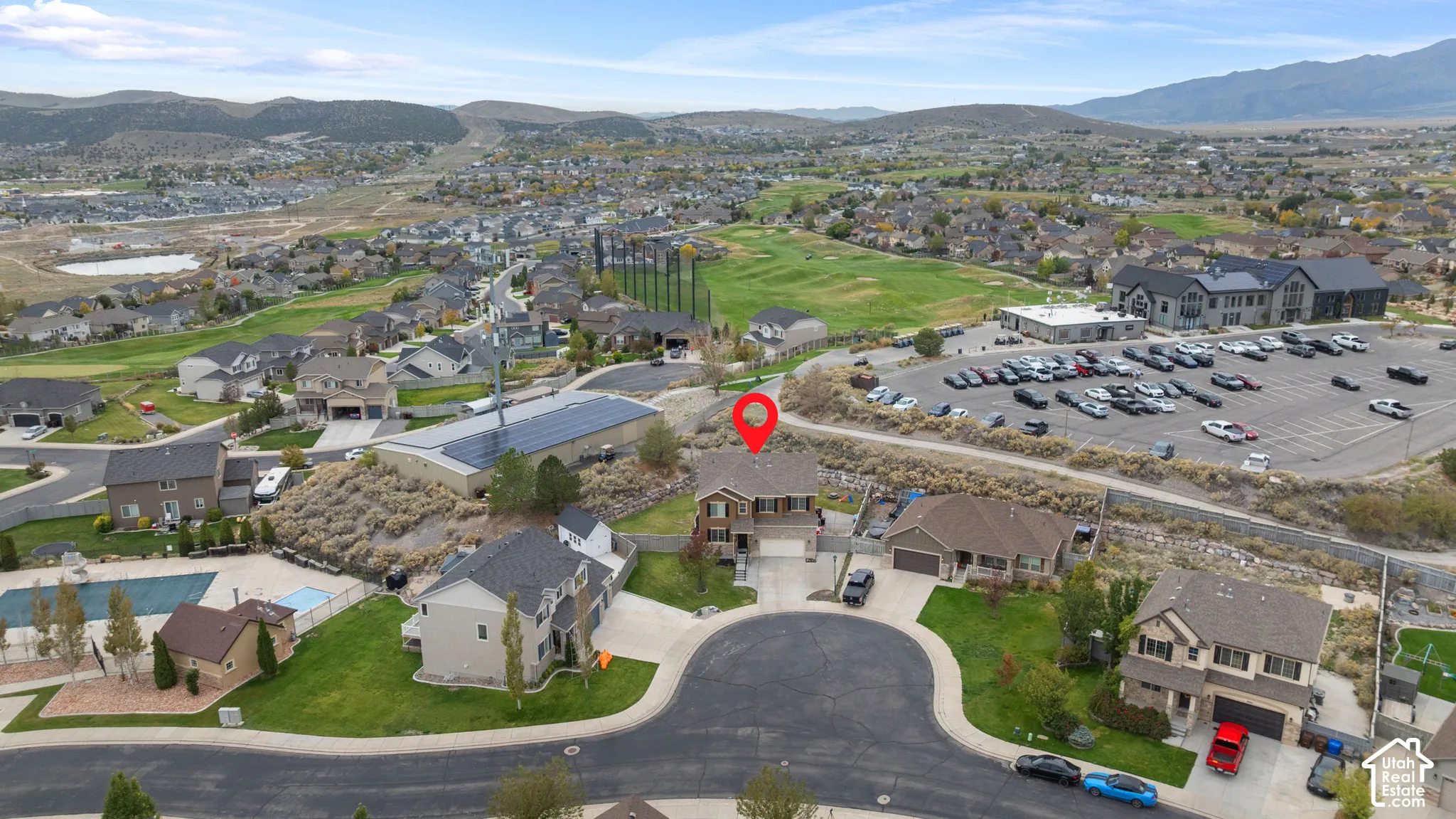 Aerial perspective featuring a two-story residence with a multi-gabled roofline, stone and composite siding exterior, attached garage, and mountain backdrop