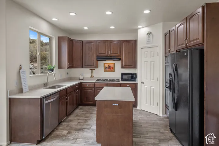 Kitchen featuring dark wood cabinetry, a center island with solid-surface countertops, recessed lighting, and tile flooring