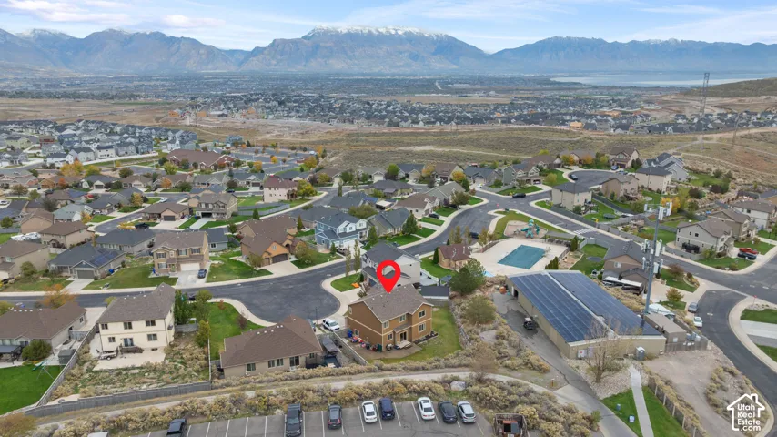 Aerial perspective featuring a two-story residential structure with a shingled roof, set against a mountainous backdrop