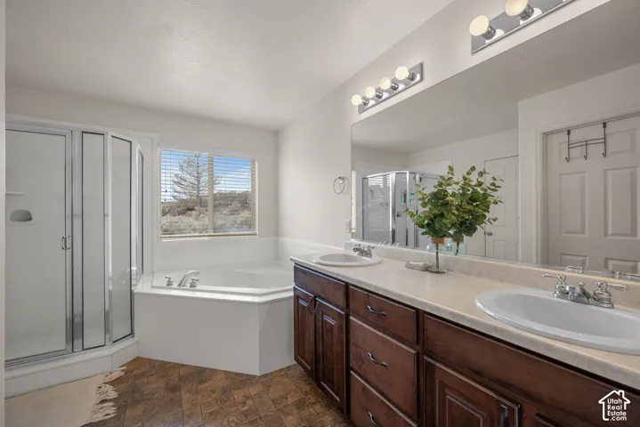 Double vanity with stone-composite countertop and integrated basins, dark wood-finish cabinetry, corner soaking tub, and separate glass-enclosed shower