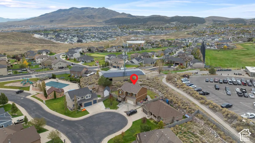 Aerial view of a two-story residence featuring an attached two-car garage, asphalt shingle roofing, and panoramic mountain scenery