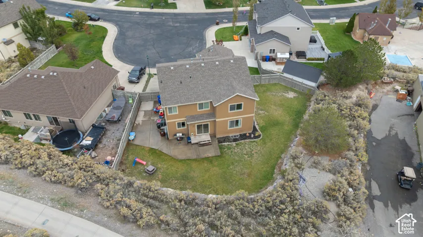 Two-story residence featuring a shingled roof, neutral-toned siding, concrete rear patio, perimeter wood fencing, and a fenced yard