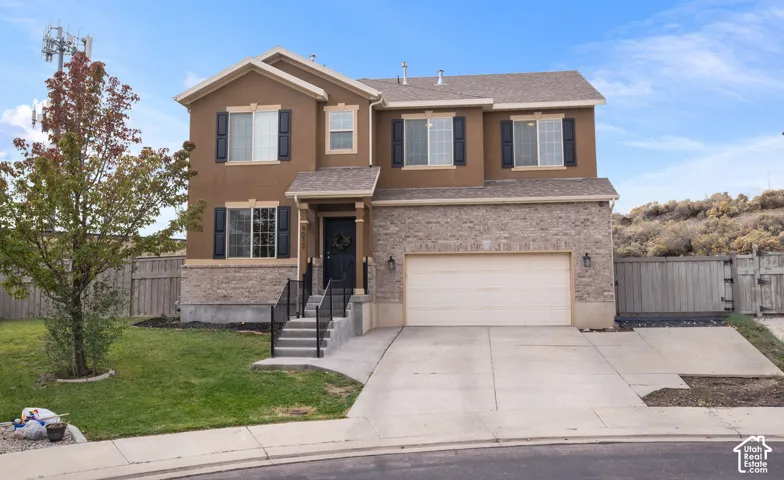 Two-story exterior featuring a stone veneer facade, stucco siding, dark window shutters, concrete driveway, and a two-car garage