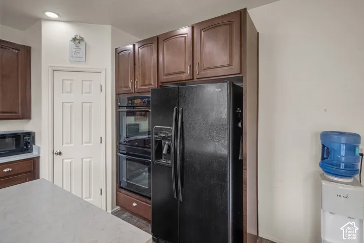 Kitchen featuring raised-panel wood cabinetry, built-in double wall ovens, recessed lighting, and a stone-surface island countertop