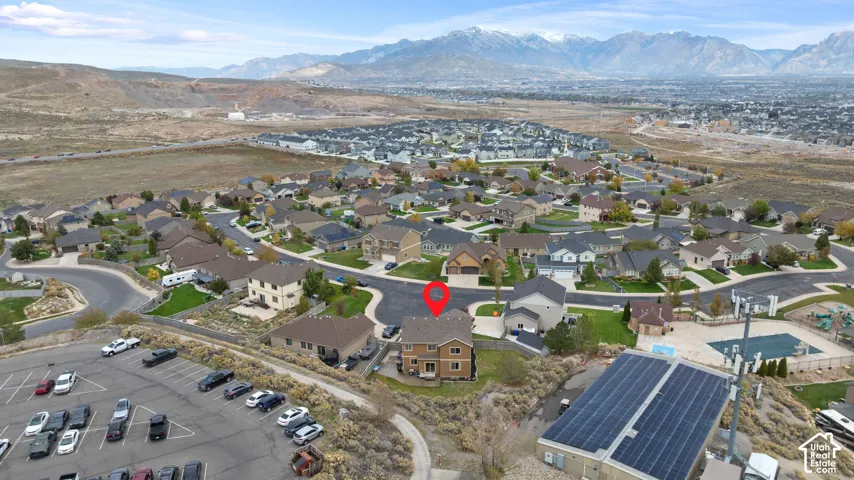Aerial perspective of a multi-story residence featuring a shingled roof, neutral-toned exterior siding, and a backdrop of mountain scenery