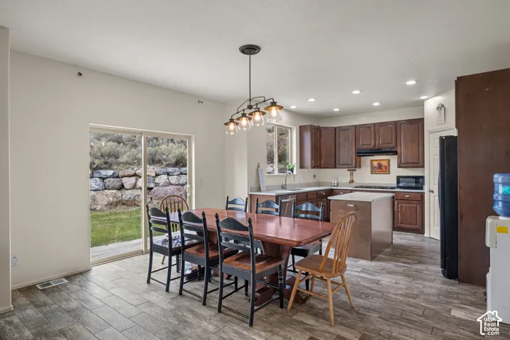 Kitchen featuring stained wood cabinetry, a central island with a quartz countertop, recessed lighting, wood-finish tile flooring, and a glass sliding door providing outdoor access