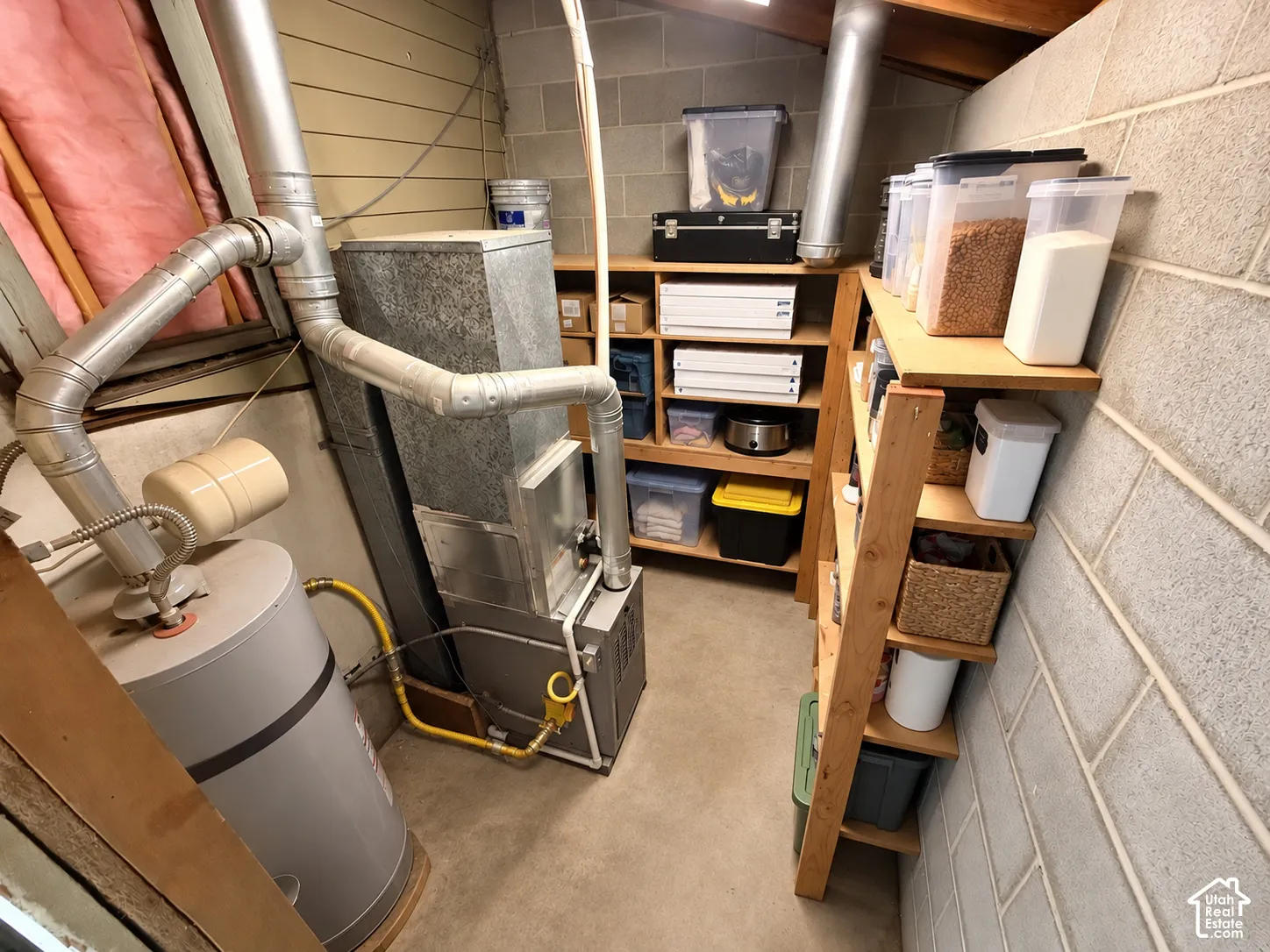 Utility space featuring a water heater, HVAC unit, concrete block walls, and built-in wood shelving
