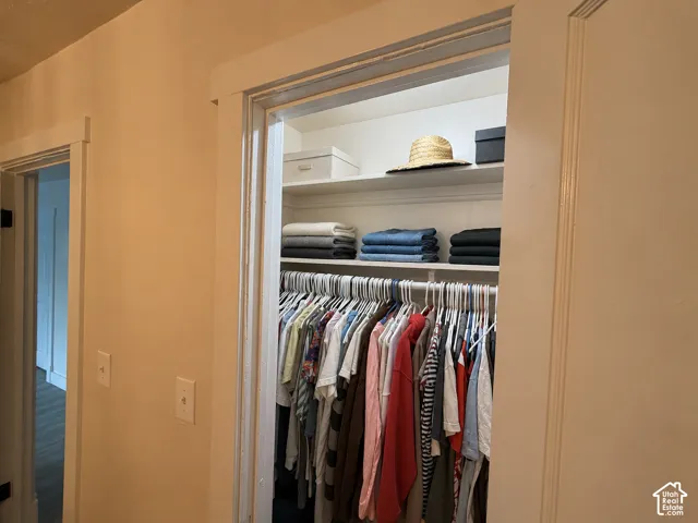 Reach-in closet featuring white wooden door casing, built-in shelving, and a horizontal garment hanging rod