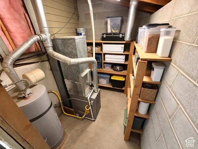 Utility space featuring a water heater, HVAC unit, concrete block walls, and built-in wood shelving