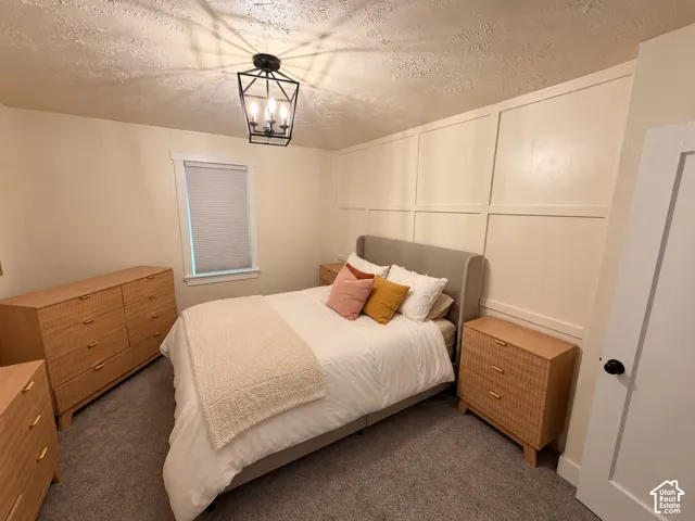 Bedroom featuring decorative wall molding, a multi-light geometric pendant fixture, and neutral carpeting
