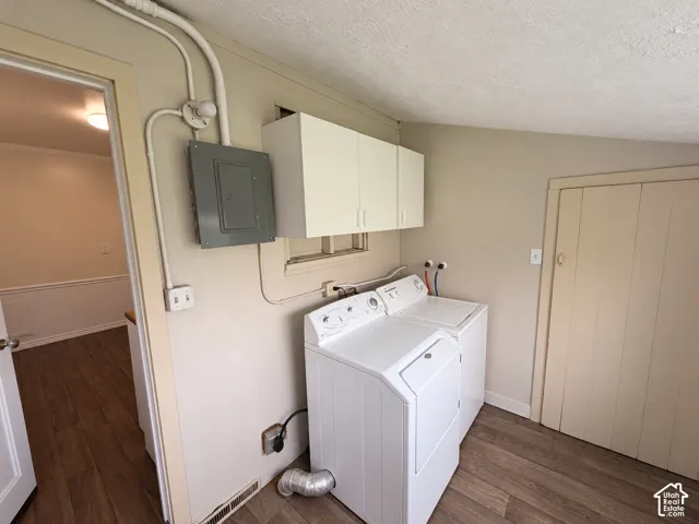 Utility room featuring wood-finish flooring, white wall-mounted cabinetry, and laundry hookups