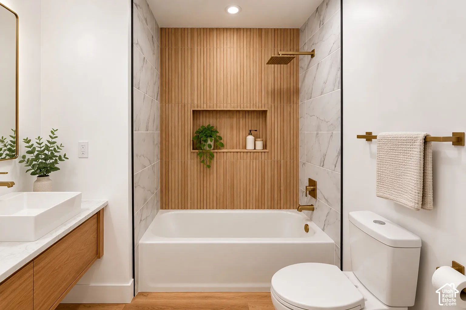 Bathroom featuring a floating wood-finish vanity, white rectangular vessel sink, tub with a vertical-slat accent wall, recessed niche, and gold-toned hardware