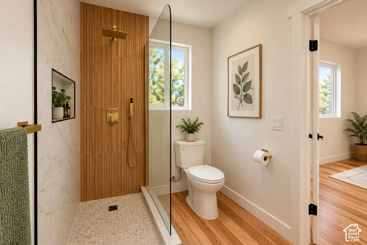 Walk-in shower featuring gold-finish fixtures, a rain showerhead, vertical wood-textured wall tile, and a pebble-stone floor, complete with a glass partition and built-in wall niche