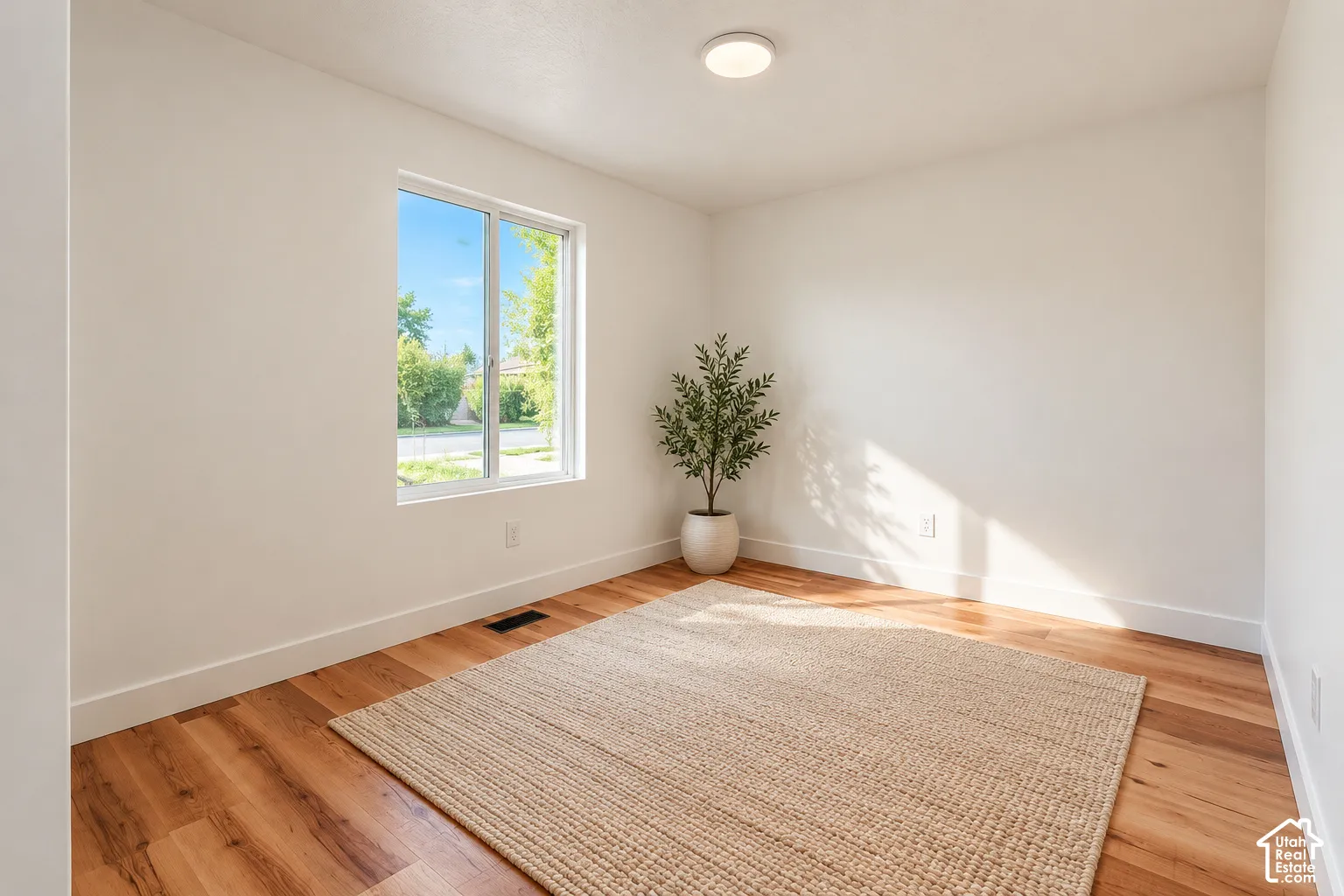 Room featuring neutral-toned walls, wood-finish flooring, and a single-pane window