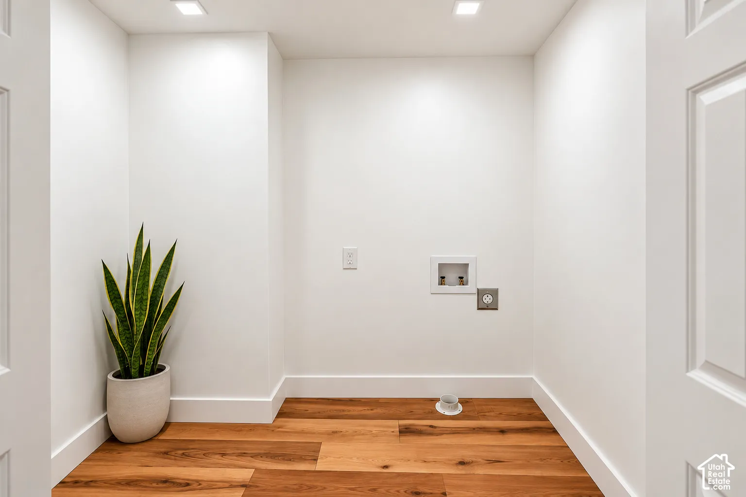 Dedicated utility alcove featuring wood-finish flooring, recessed lighting, and wall-mounted water and power hookups