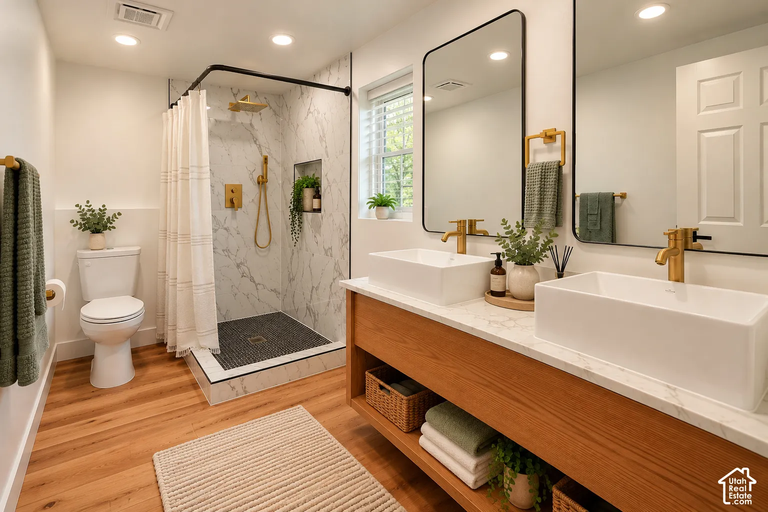 Double vanity featuring a wood-finish base, dual rectangular vessel sinks, and stone-look countertops, complemented by a walk-in shower with floor-to-ceiling stone-look wall tile, a recessed shower niche, and brass-tone fixtures throughout