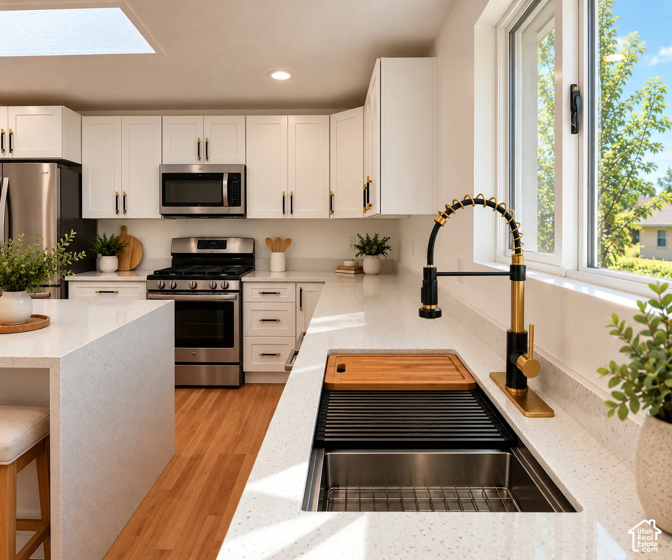 Kitchen featuring white shaker-style cabinetry, a quartz waterfall island, stainless steel appliances, a high-arc pull-down faucet, and wood-finish flooring