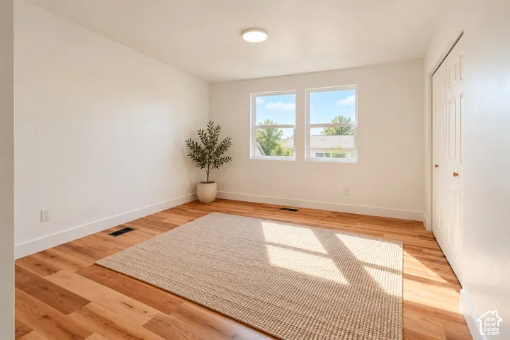 Room featuring wood-finish flooring, dual windows, and closet with double doors
