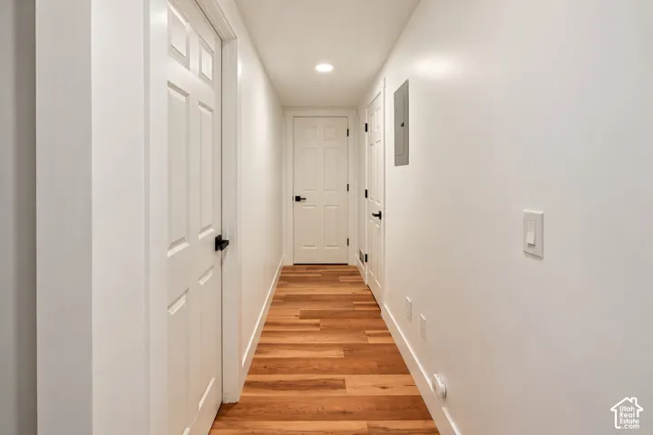 Hallway featuring wood-finish flooring, six-panel interior doors, and matte black hardware