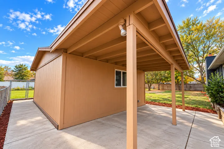 Detached exterior structure with a covered concrete patio, exposed rafter tail roof construction, and vertical panel siding
