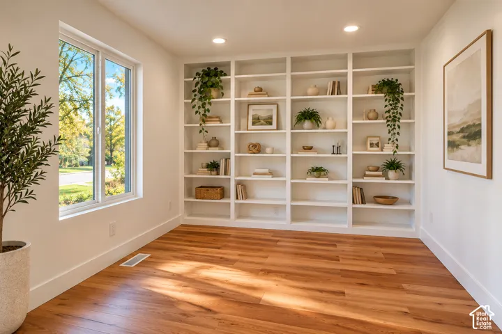 Built-in floor-to-ceiling white shelving, wood-finish flooring, and recessed ceiling lighting