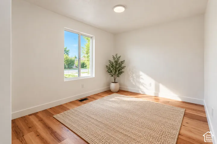 Room featuring neutral-toned walls, wood-finish flooring, and a single-pane window