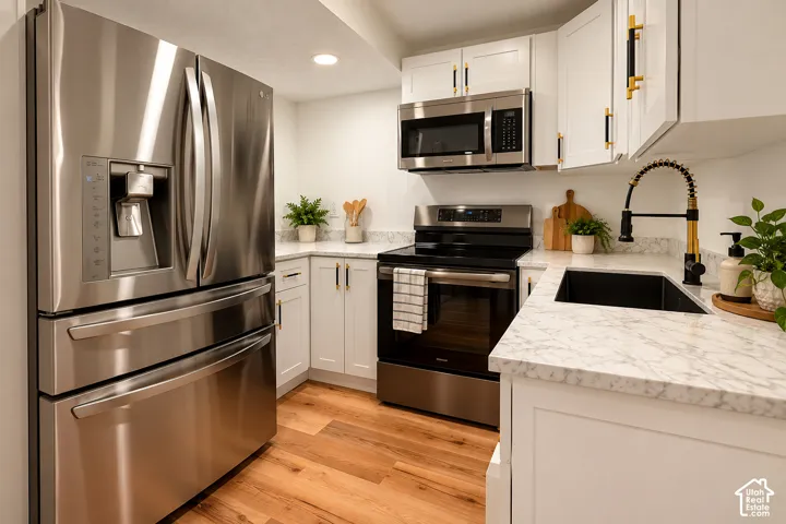 Kitchen featuring white shaker-style cabinetry, stone-finish countertops, stainless steel appliances, wood-finish flooring, and a matte black pull-down faucet