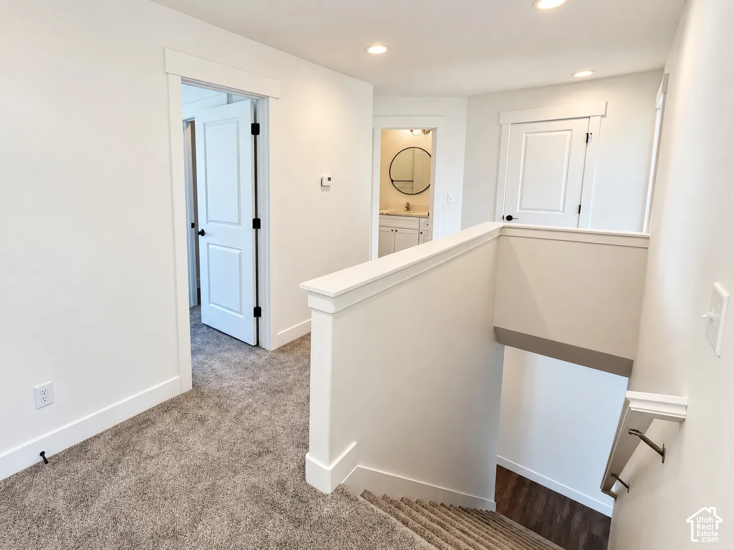 Interior landing featuring neutral-toned carpeting, recessed ceiling lighting, crisp white trim, and paneled interior doors
