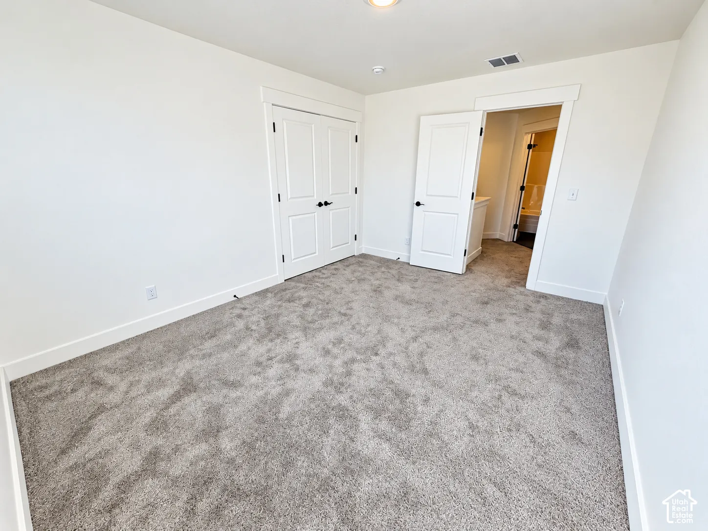 Neutral-toned wall-to-wall carpeting, two-panel interior doors with matte black hardware, and crisp white trim throughout